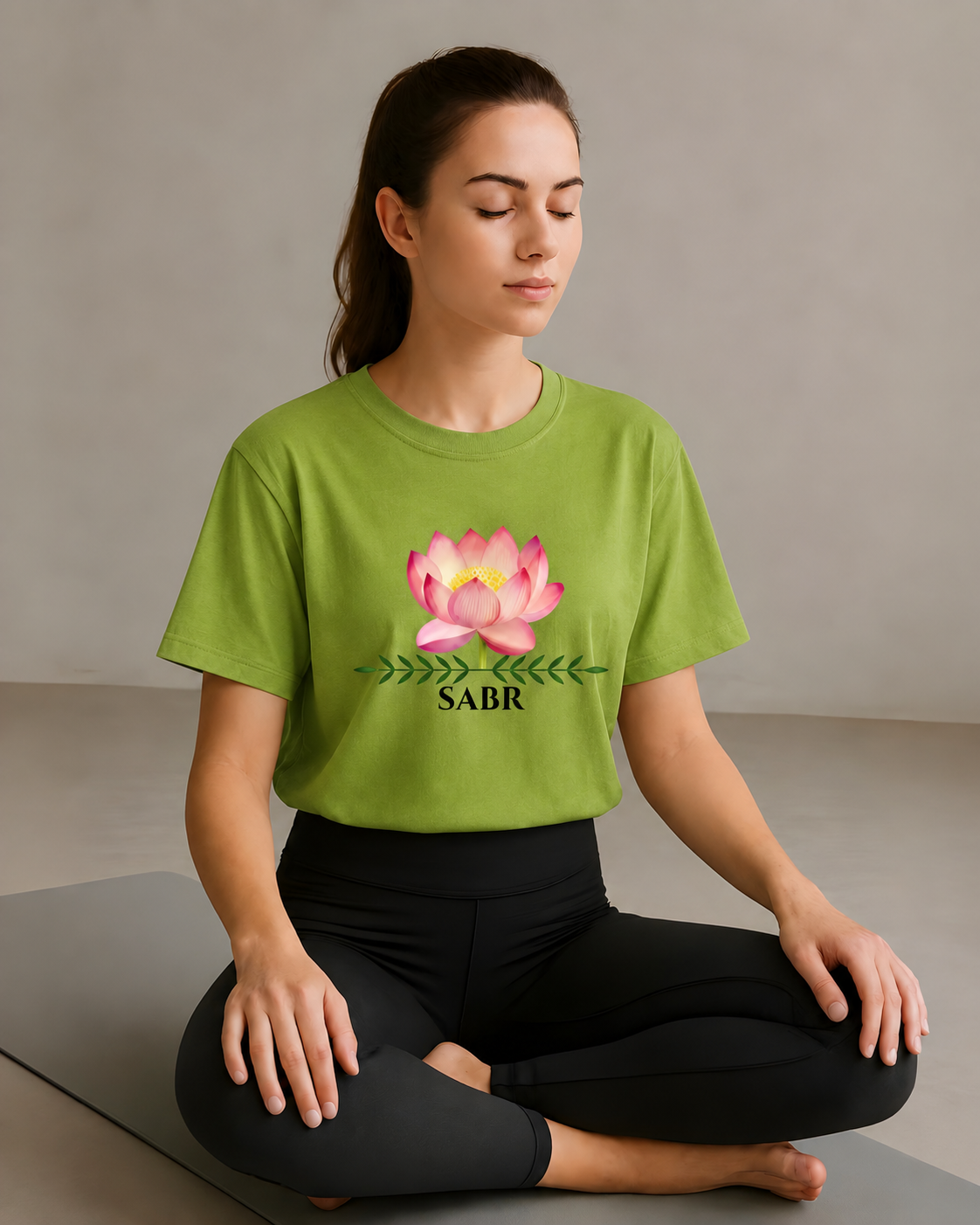Woman meditating in a lime green Sabr yoga t-shirt with lotus flower graphic