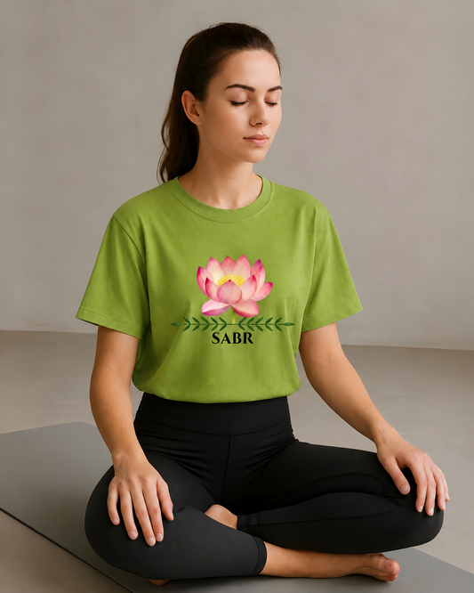 Woman meditating in a lime green Sabr yoga t-shirt with lotus flower graphic