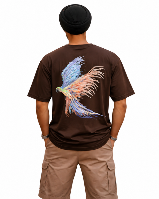 A man viewed from behind wearing a dark brown t-shirt with a large colorful graphic of a bird on the back, paired with khaki cargo shorts and a black beanie, against a plain white background.